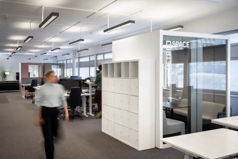 Office view with Vetrospace pods and white storage lockers in an open workspace.