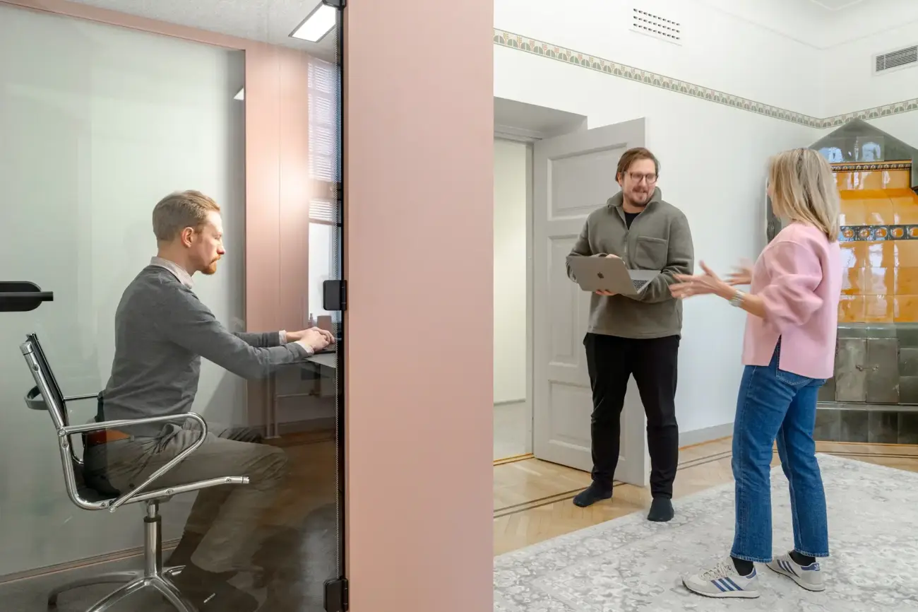 Two employees interacting near a Vetrospace pod in a modern workspace, while one is workin inside the pod.
