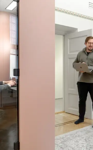 Two employees interacting near a Vetrospace pod in a modern workspace, while one is workin inside the pod.